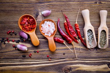 Çeşitli otlar ve baharatlar ahşap arka plan üzerinde tahta kaşıklar içinde.