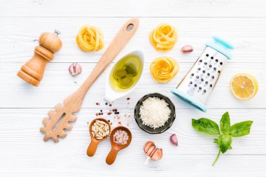 Beyaz ahşap zemin üzerine ev yapımı pesto makarna için malzemeler.