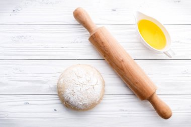 Çiğ pizza hamuru ve ahşap arka planda merdane.