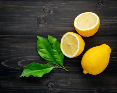 Taze limon ve limon yaprakları koyu ahşap arka plan üzerinde.