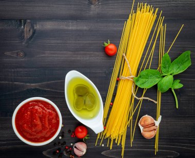 Siyah ahşap zemin üzerine ince spagetti. Sarı İtalyan makarna malzemelerle. İtalyan gıda ve menü kavramı.