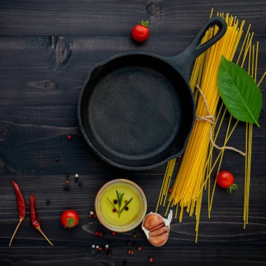 Siyah ahşap zemin üzerine ince spagetti. Sarı İtalyan makarna malzemelerle. İtalyan gıda ve menü kavramı.