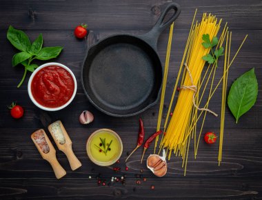 Siyah ahşap zemin üzerine ince spagetti. Sarı İtalyan makarna malzemelerle. İtalyan gıda ve menü kavramı.