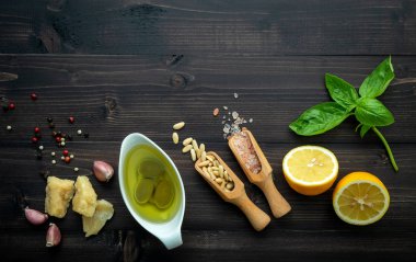 Koyu ahşap zemin üzerine yeşil pesto sos için malzemeler.