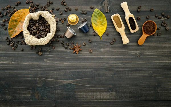 Kaffebönor, kaffe kapsel och kaffepulver på mörkt trä ba — Stockfoto