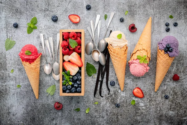 Various of ice cream flavor in cones with berries in wooden box setup on concrete background . Summer and Sweet menu concept.