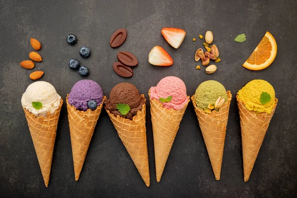 Various of ice cream flavor in cones blueberry ,pistachio ,almond ,orange and chocolate setup on dark stone background . Summer and Sweet menu concept.