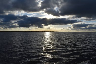 Koyu mavi tonları parlak renkli gökyüzü. Nehirde gün batımı. Güneşin suya yansıması. 