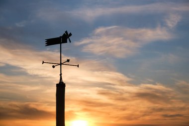 Günbatımında dekoratif yel değirmeniyle vanenin silueti.