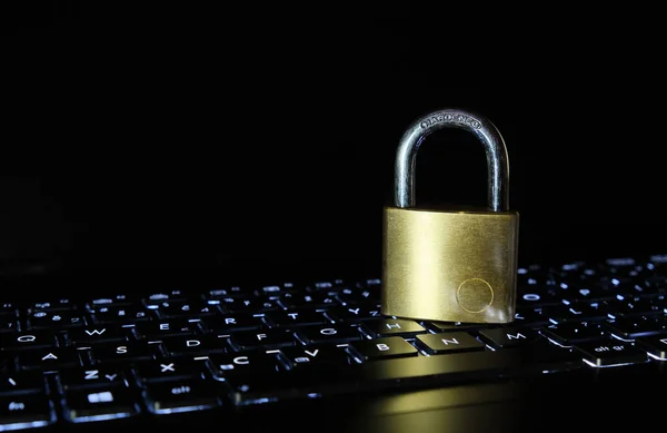Laptop klavyesinde sertleştirilmiş çelikten yapılmış asma kilit. Güvenlik ve siber suç kavramı.