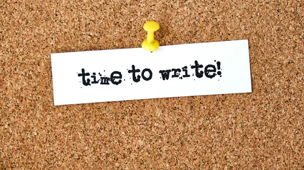 Time to write. Text written on a piece of paper or note, cork board background.