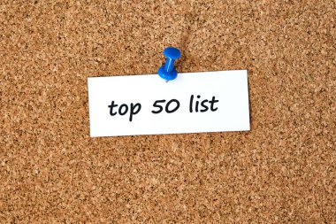 İlk 50 'de. Bir parça kağıda veya nota yazılmış metin, tıpa tahtası arkaplanı.