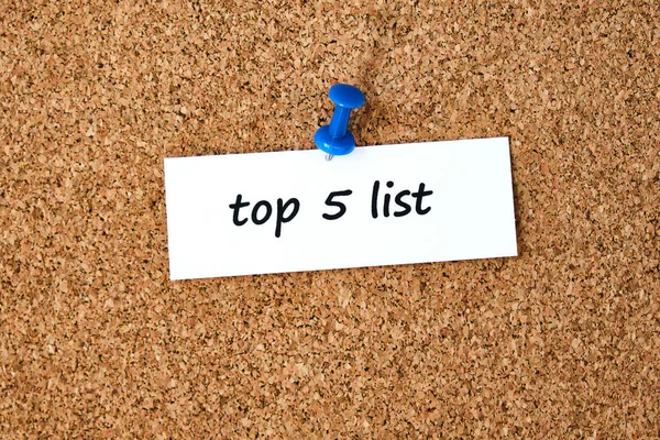 İlk 5 'te. Bir parça kağıda veya nota yazılmış metin, tıpa tahtası arkaplanı.