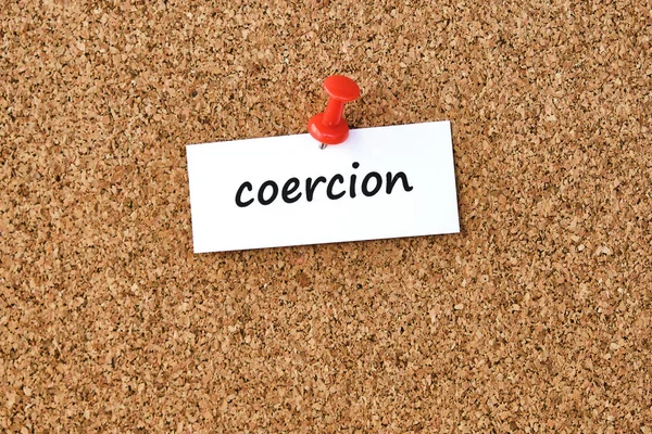 Coercion. Word written on a piece of paper or note, cork board background.