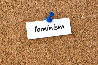 Feminizm. Bir parça kağıda veya nota yazılmış sözcük, mantar tahtası arka planı.
