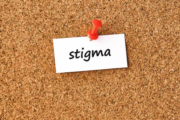Stigma. Bir parça kağıda veya nota yazılmış sözcük, mantar tahtası arka planı.