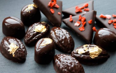 Koyu çikolata pralin ve bonbon yenebilen altın ve kurutulmuş çilek ile dekore.