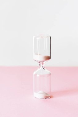 Pembe ve beyaz arka planda kum saati, kum saati ampulünden akan kum saati. asgari kavram.