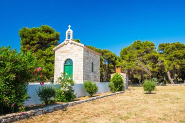 Hırvatistan, Dugi Otok Adası, güneşli bir günde çam ağaçları arasında taş sahildeki veli Rat 'ın güzel eski taş Kilisesi, Akdeniz manzarası