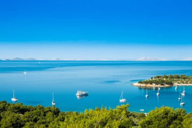 Hırvatistan'ın Murter adasındaKi Kosirina plaj lagünü, mavi denizde yelkenli tekneler ve yatlar demirledi panoramik manzara