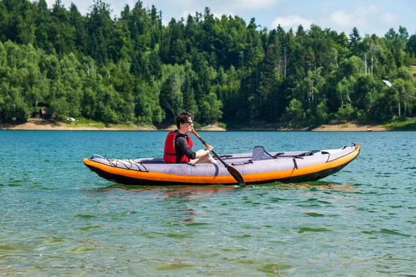 Young active woman kayaking in inflatable kayak on lake Lokve, in Gorski kotar, Croatia. Adventurous experience on a beautiful sunny day.