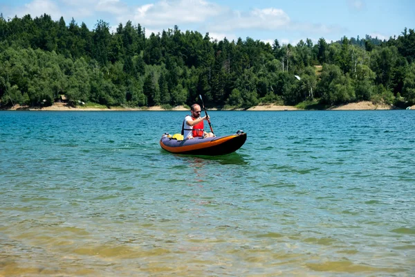 Man kayaking in inflatable kayak on lake Lokve, in Gorski kotar, Croatia. Adventurous experience on a beautiful sunny day.