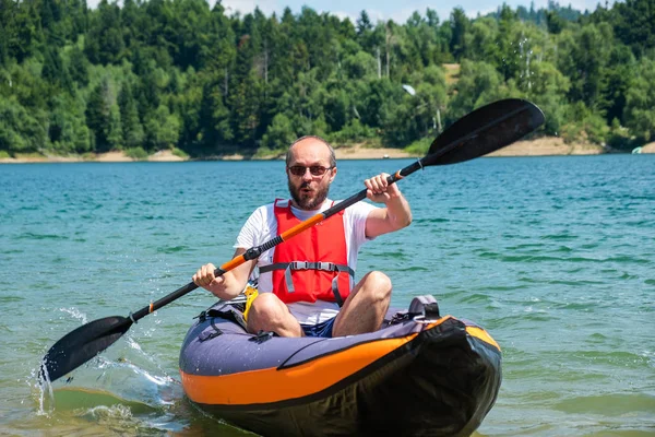 Man kayaking in inflatable kayak on lake Lokve, in Gorski kotar, Croatia. Adventurous experience on a beautiful sunny day.