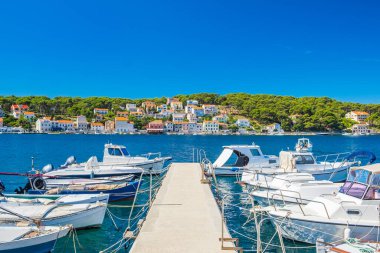 Hırvatistan 'ın Adriyatik kıyısındaki Losinj adasındaki Mali Losinj limanı, rıhtımdaki tekneler ve arka plandaki eski evler