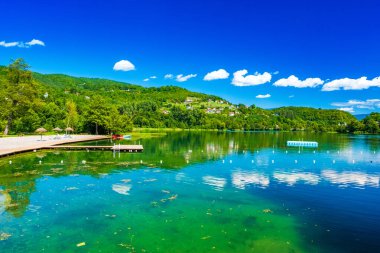 İnanılmaz yeşil Plivsko Gölü Jezero, Jajce, Bosna-Hersek, su yüzeyinde ahşap yansıması