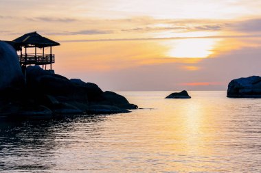 Tayland cennet adasında güzel gün batımı. Deniz ve güneşin arka planına karşı taşlar ile bir dağ üzerinde Tropikal bungalov