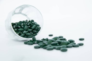 Spirulina tabletler beyaz arka plan üzerinde bir cam