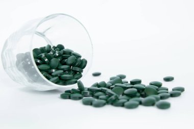 Spirulina tabletler beyaz arka plan üzerinde bir cam