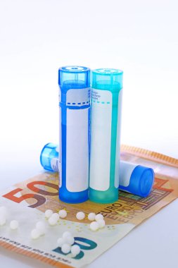 Homeopathy tubes, granules and banknote concept isolated studio lighting clipart