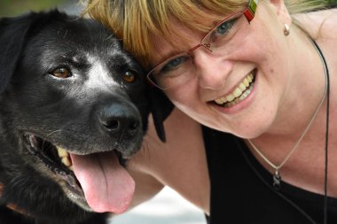 Gözlüklü Siyah labrador köpek yanında gülümseyen genç kadın