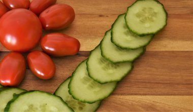  Olgun tüm mini domates ve ahşap bir arka planda taze salatalık Dilimleme