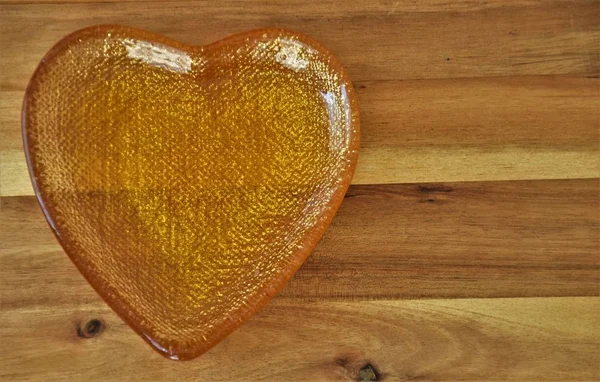 liquid flower honey in a golden heart-shaped cup on a wooden table