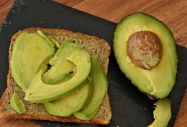 Avocado Met Bot Brood Een Zwarte Plaat — Stockfoto