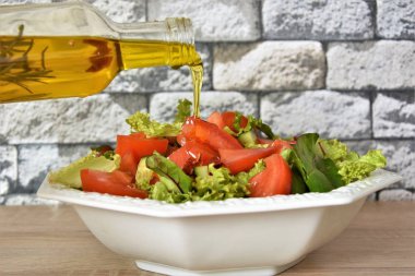 beyaz bir tabakta bitkisel yağ ve sebze salatası