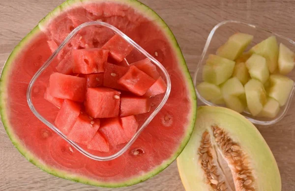 half a melon with seeds and a ripe watermelon half and cut into cubes in a glass bowl