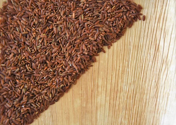 grains of red long grain rice on a wooden palm plate