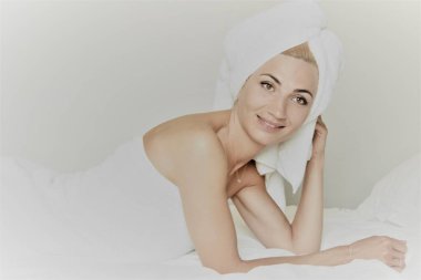 spa salonunda yatan beyaz terry bez üzerinde yatan genç sevimli kadın