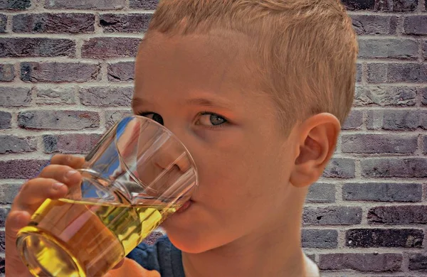 boy drinks juice from a glass on a brick wall background