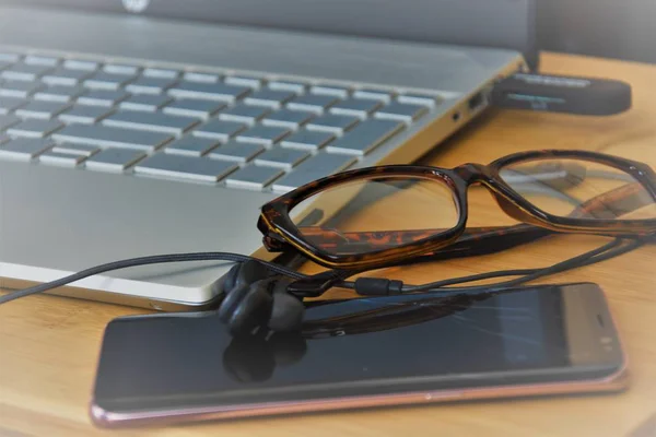 keypad, glasses, headphones and smartphone on a wooden table