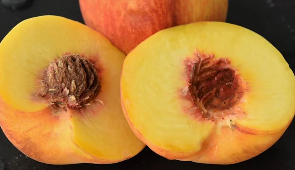 two, half ripe peach on a black background