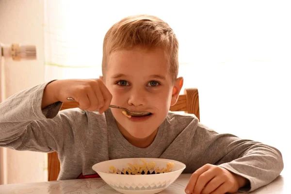 Boy Sits Chair Table Eats Pasta Plate — ストック写真