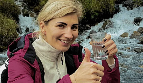 Ung Kvinna Med Ryggsäck Nära Bergsbäck Plockar Upp Rent Vatten — Stockfoto