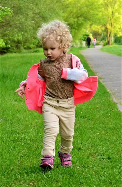草の上を歩く小さな巻きブロンドの女の子 — ストック写真