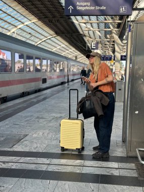 Berlin, Almanya, 11 Eylül 2025 Bavullu uzun saçlı kadın, Berlin istasyonunda tren bekliyor..