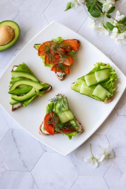 Hafif bir arka plan üzerinde avokado, domates ve salatalık ile Vejetaryen sandviç