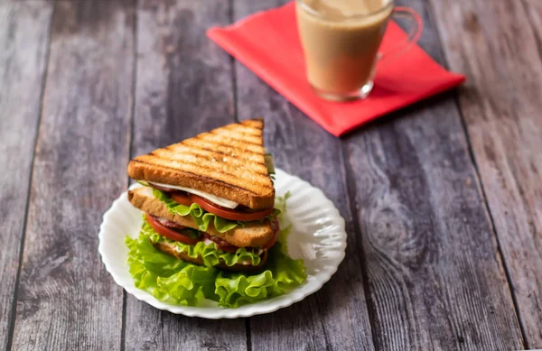 Сендвіч з сиром, помідорами, огірком, ковбасою та салатом на дерев'яному фоні. Кава з молоком Горизонтальна орієнтація — стокове фото